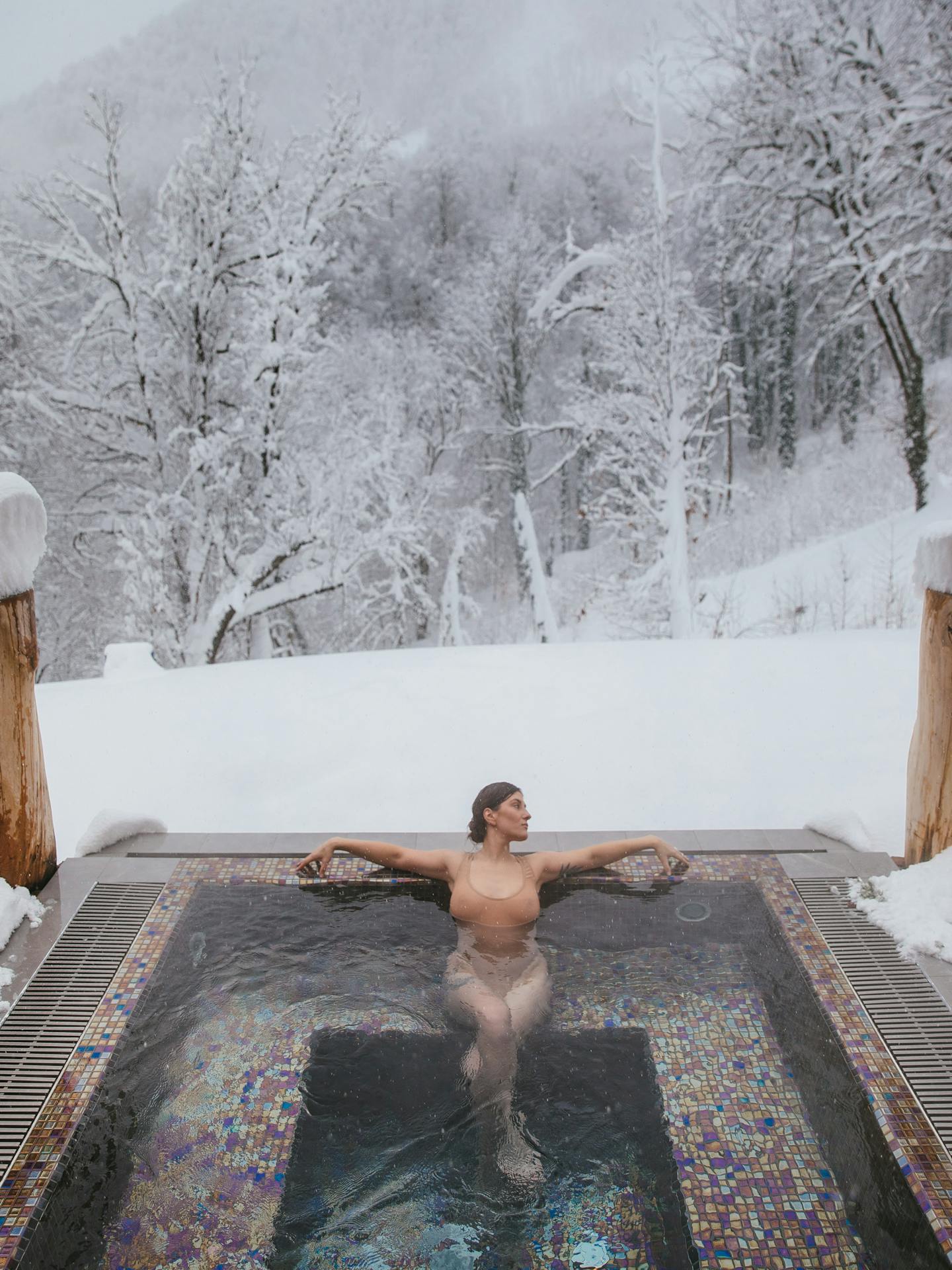 Woman in a Hot Tub Near a Snow Covered Forest